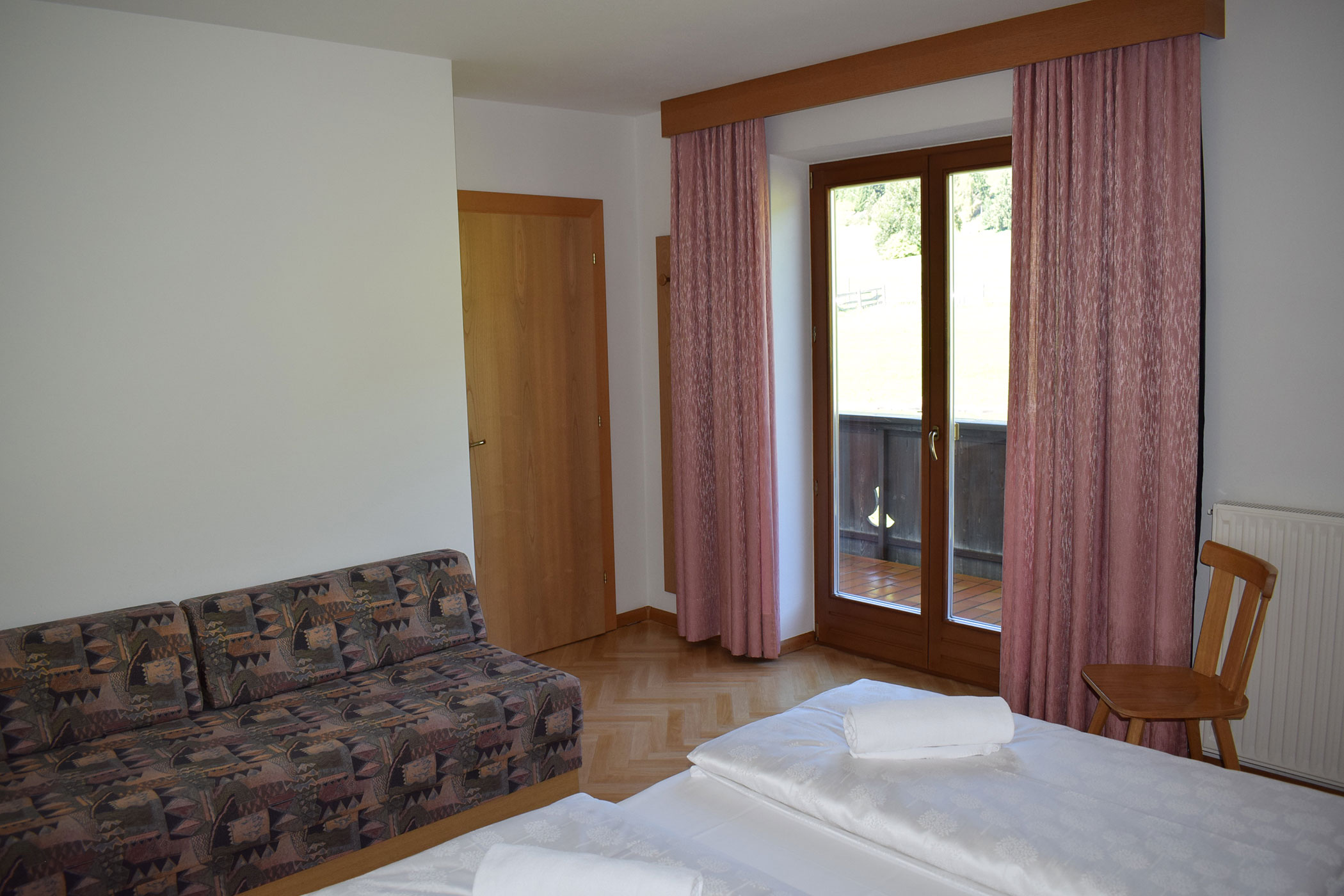 Un letto bianco con un piumone bianco in una stanza luminosa.