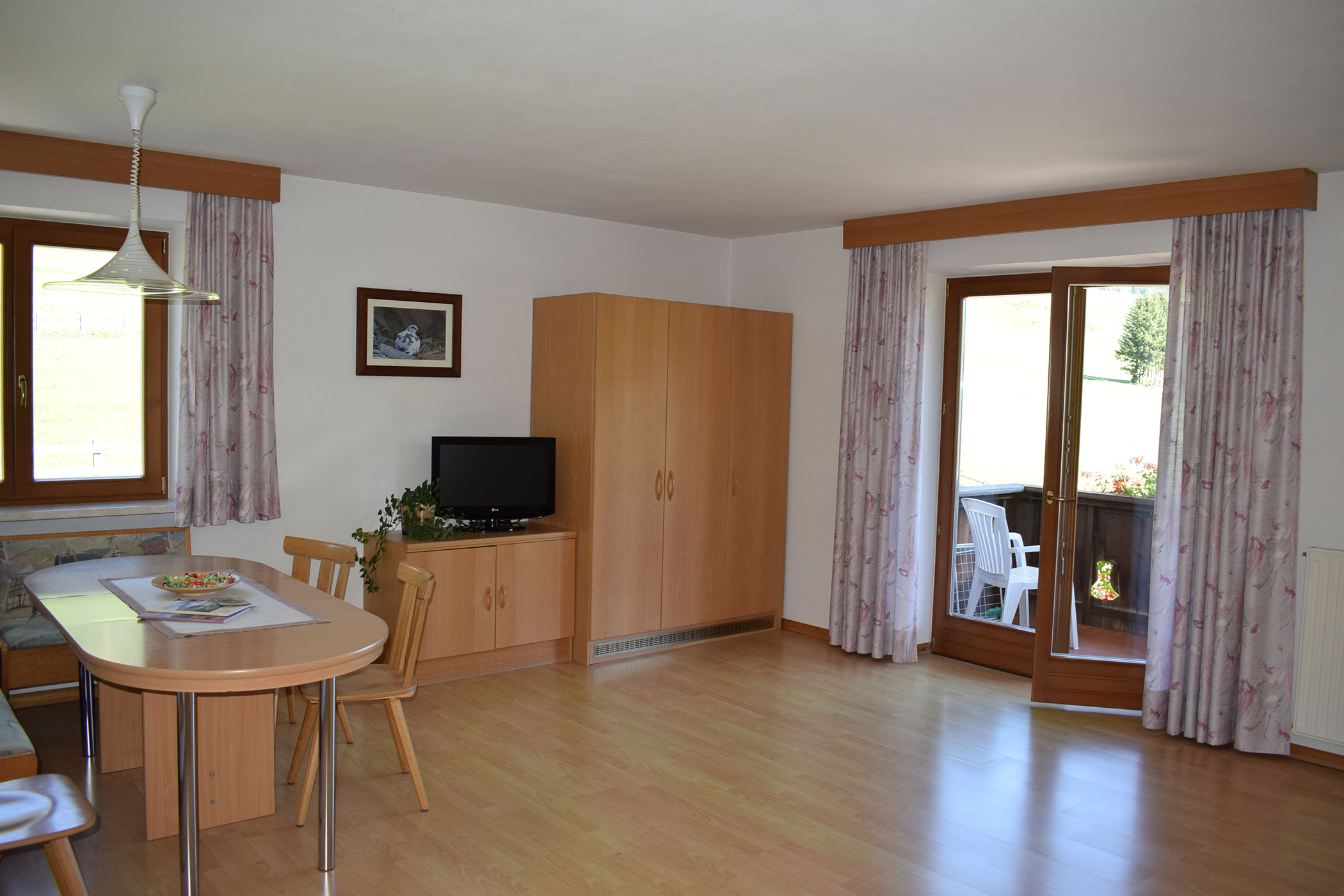 Un soggiorno con tavolo, sedie e televisione.