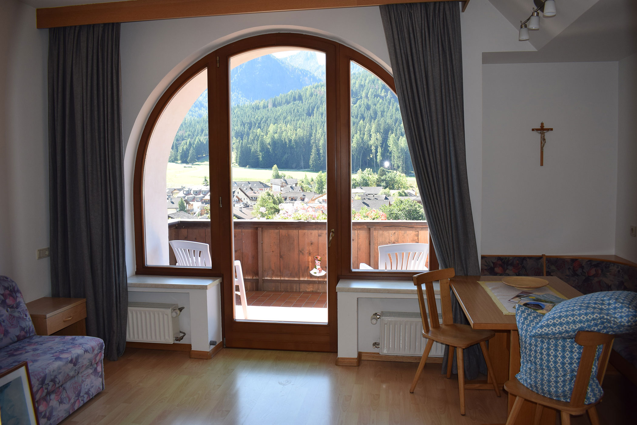 Soggiorno con pavimento in legno nei toni caldi del marrone e ampia finestra.