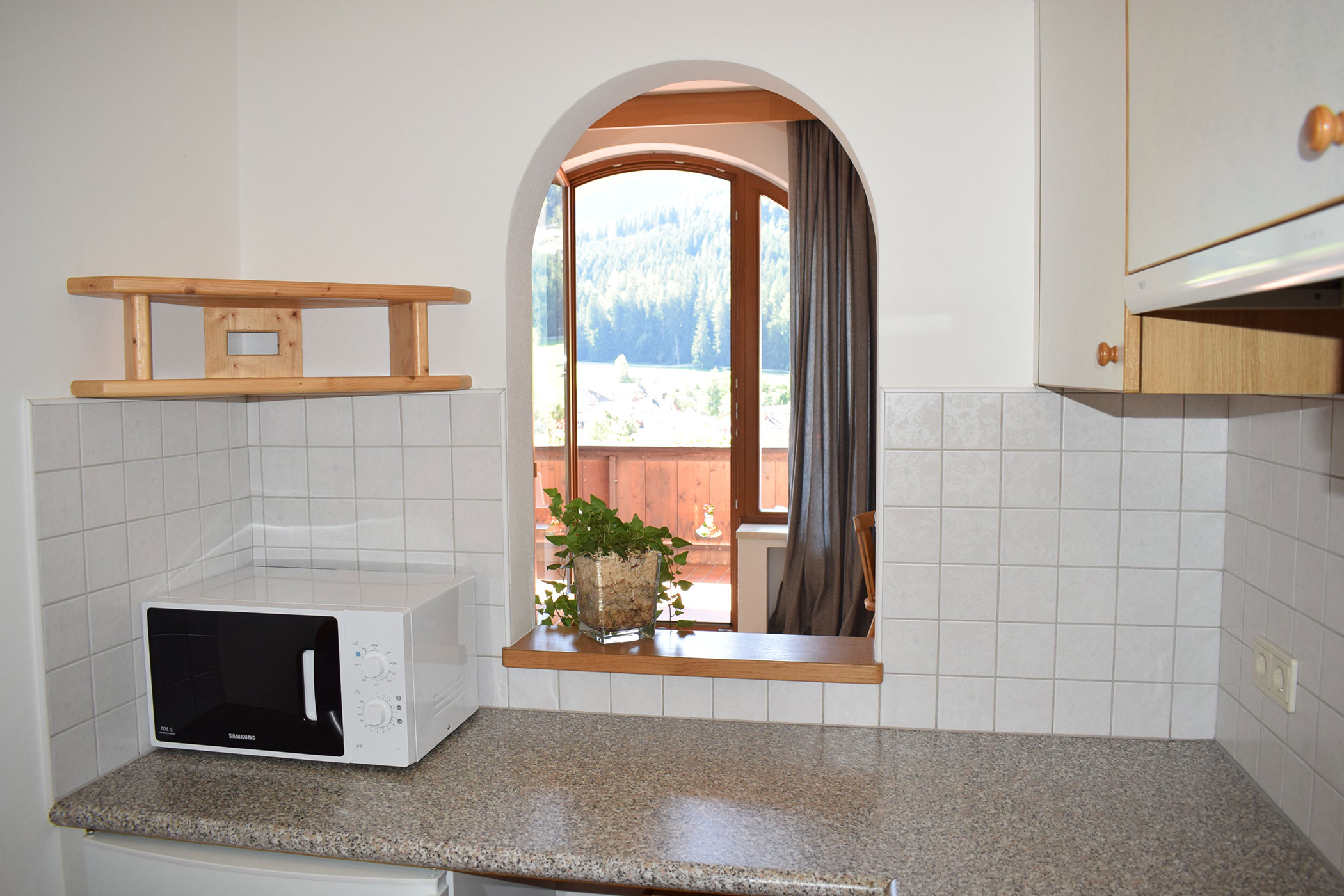 Una cucina con forno a microonde e una finestra che lascia entrare la luce del giorno.